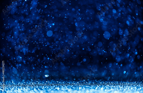 blue sequins fall on a black background. holiday, shine. texture with bokeh