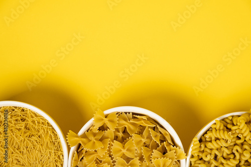 Close up of several types of dry pasta in a plate on yellow background photo