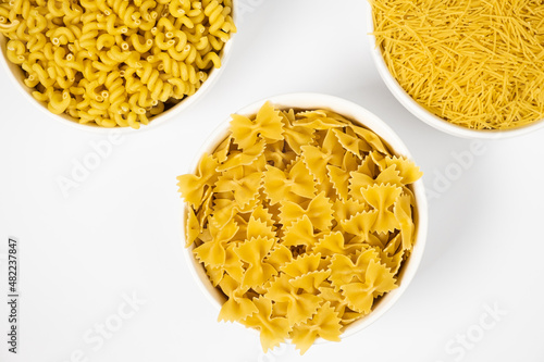 Close up of several types of dry pasta in a plate on white background photo