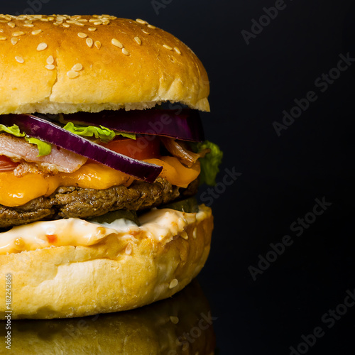 hamburger with lettuce, cheese, onion and homemade cutlet. close-up on a black background.