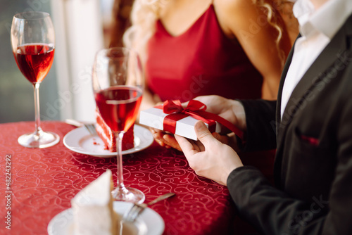 Valentine's Day concept. Exchange of gifts. Beautiful young couple celebrating Valentine's Day  in the restaurant. Hug, kiss and enjoy spending time together.
