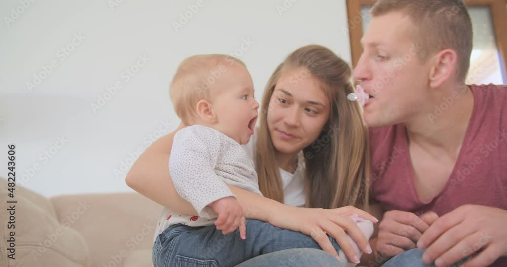 Parents entertaining their daughter with a pacifier Parents entertaining their daughter with a pacifier