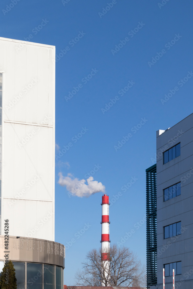 View of a factory chimney between two buildings. View of a factory chimney between two buildings.