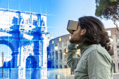 Fotobehang Young man in Piazza del Colosseo (Rome) looks at a virtual reconstruction with a cardboard viewer