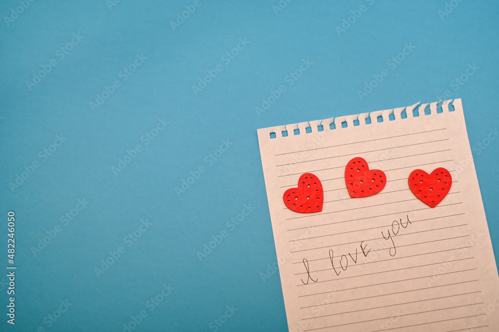 I love you on a piece of paper with hearts. on a blue background.