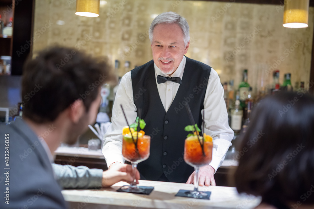 Bartender serving cocktails to a young couple