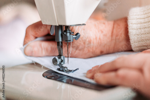 Close-up of womans hand sewing on the sewing machine.