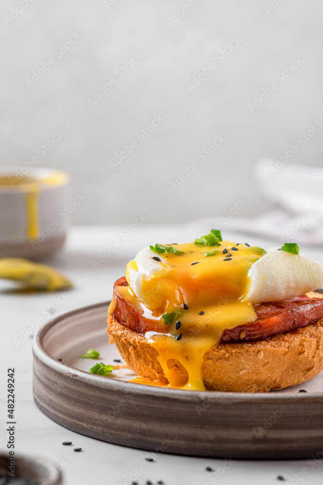Egg benedict. Poached egg, ham, hollandaise sauce, onion on slice toast for tasty breakfast. vertical orientation. Egg benedict. Poached egg, ham, hollandaise sauce, onion on slice toast for tasty breakfast. vertical orientation.