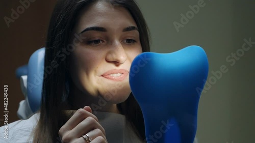 Young female patient trying on aligners looking in the mirror at the dentist's office
