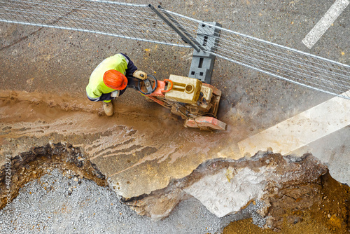 obrero de la construcción cortando asfalto de una calle con una máquina cortadora