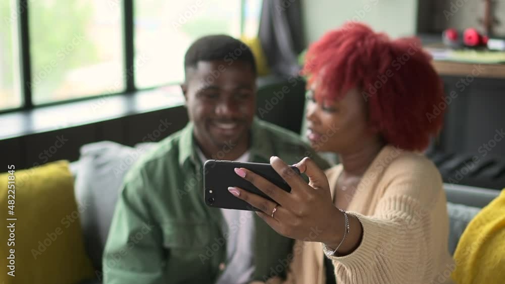 Man communicate vid video call while black girlfriend hold cell phone Spbd. African friendly male talk chat on distant family meeting, sit on cozy sofa. Blurred afro couple discuss Man communicate vid video call while black girlfriend hold cell phone Spbd. African friendly male talk chat on distant family meeting, sit on cozy sofa. Blurred afro couple discuss
