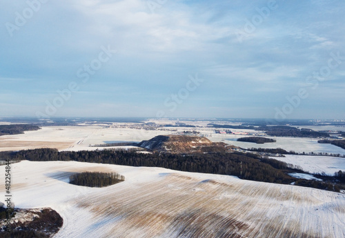 Top view photo of a winter suburban landscape with snowy fields  meadows and forests