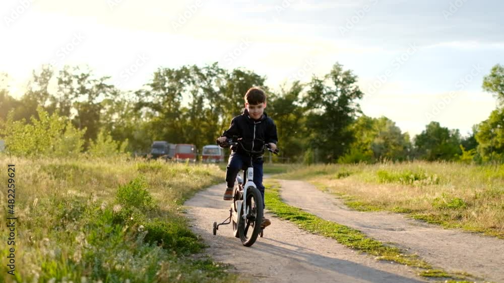 A child learns to ride a bike in a natural park. Happy boy rides a bicycle, has fun in nature. Active sport family vacation. A child learns to ride a bike in a natural park. Happy boy rides a bicycle, has fun in nature. Active sport family vacation.