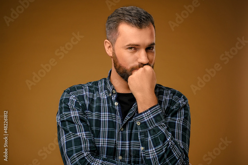 Handsome man with beard covering his mouth with one hand