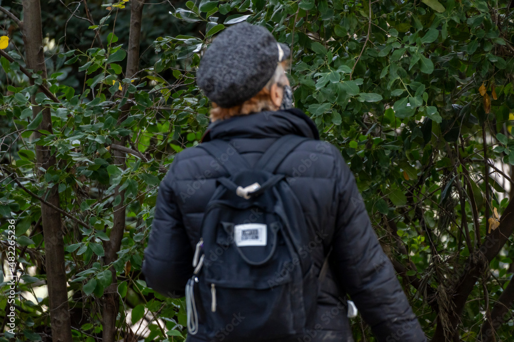 Femme avec un sac a dos et un chapeau qui regarde vers les arbres 