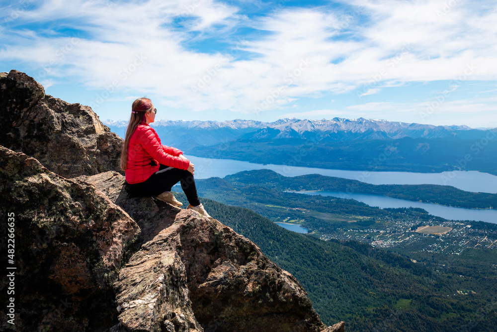 Mujer turista sentada en la cima del cerro Catedral admirando las vistas de los lagos de Bariloche. Patagonia Argentina