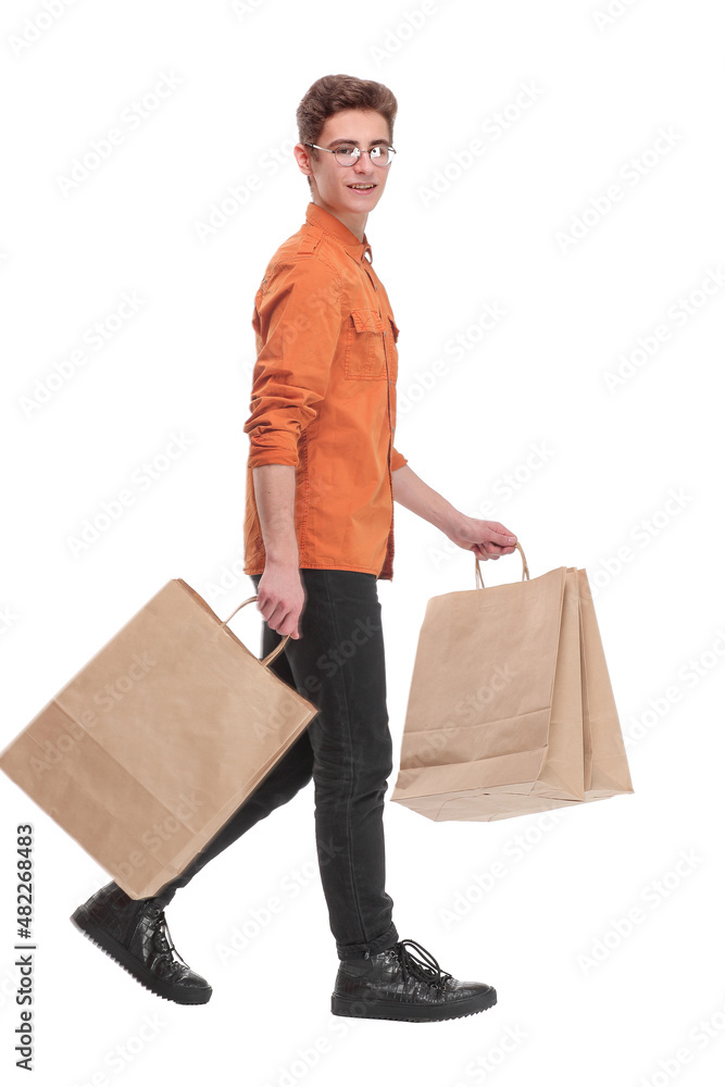 Side view of going young man in bright shirt with shopping bags. Side view of going young man in bright shirt with shopping bags.