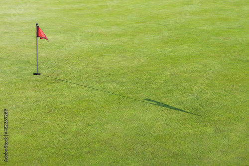 A red flag in the hole on the golf course.