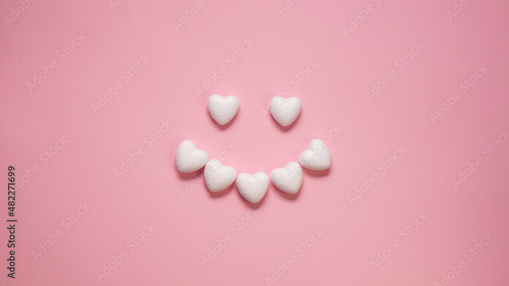 Creative layout made with little white hearts in the shape of two eyes and smiling lips on a pink background. Minimal romantic. Valentine's Day Mothers Day concept.