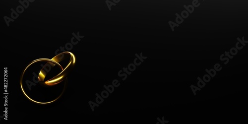 Two interlocked golden wedding or engagement rings isolated on black background, marriage, proposal or love concept with copy space