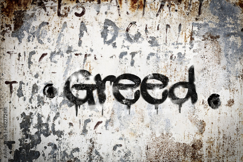 The word greed spray painted on grungy concrete background. Weather washed.