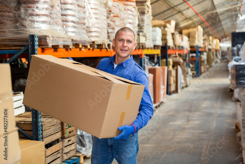 Portrait of loader with a large box in his hands in a store warehouse