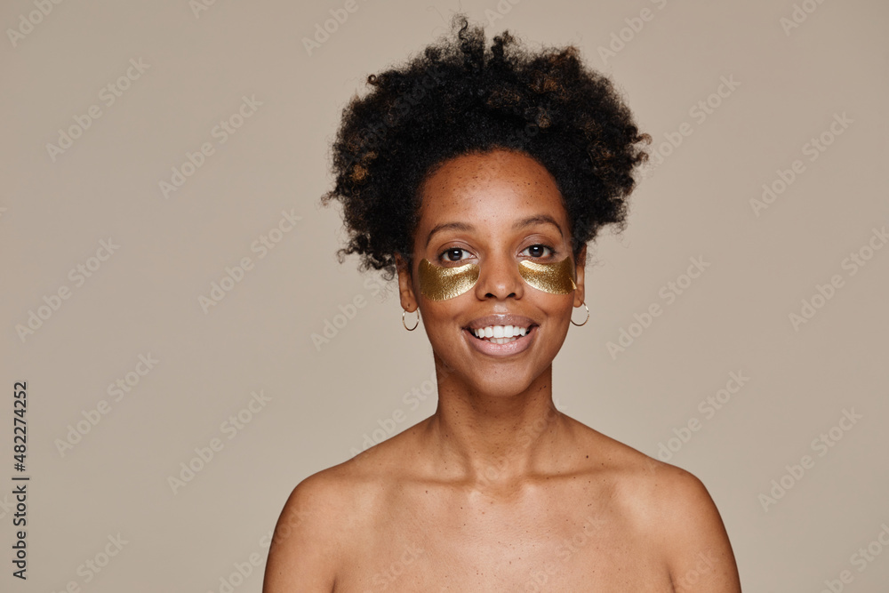 Minimal portrait of young African-American woman using face patches against neutral background, copy space