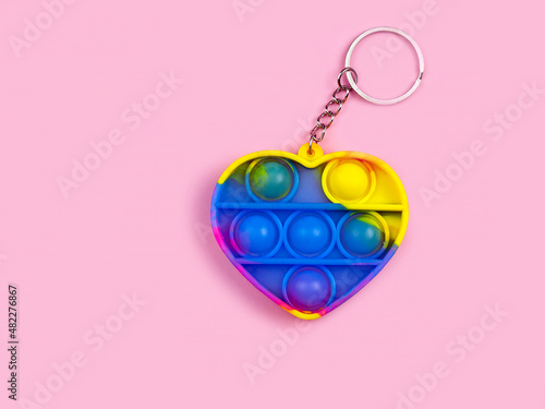 Anti-stress sensory toy Rainbow heart on a pink background. New multicolored bubbles.