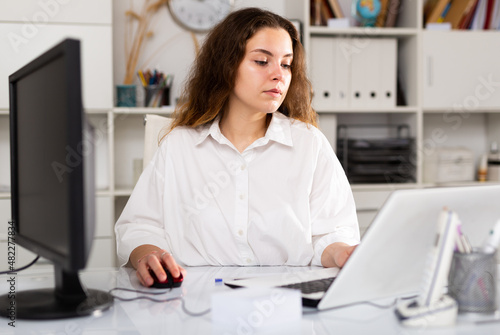 Portrait of young elegant confident female office worker in a company at a modern workplace