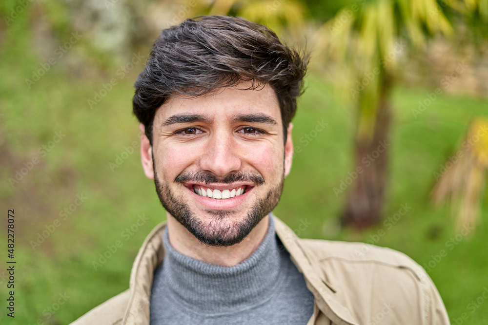 Cheerful bearded man sitting on bench and looking at camera Cheerful bearded man sitting on bench and looking at camera