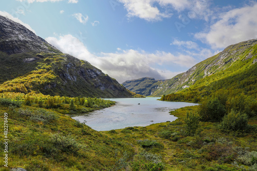 Tranquil Norwegian mountain lake surrounded by green foliage 