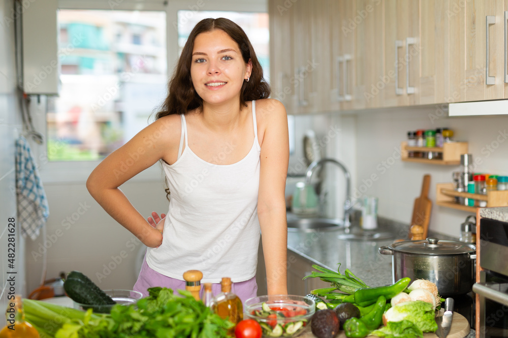Attractive young woman in casual clothing standing in kitchen