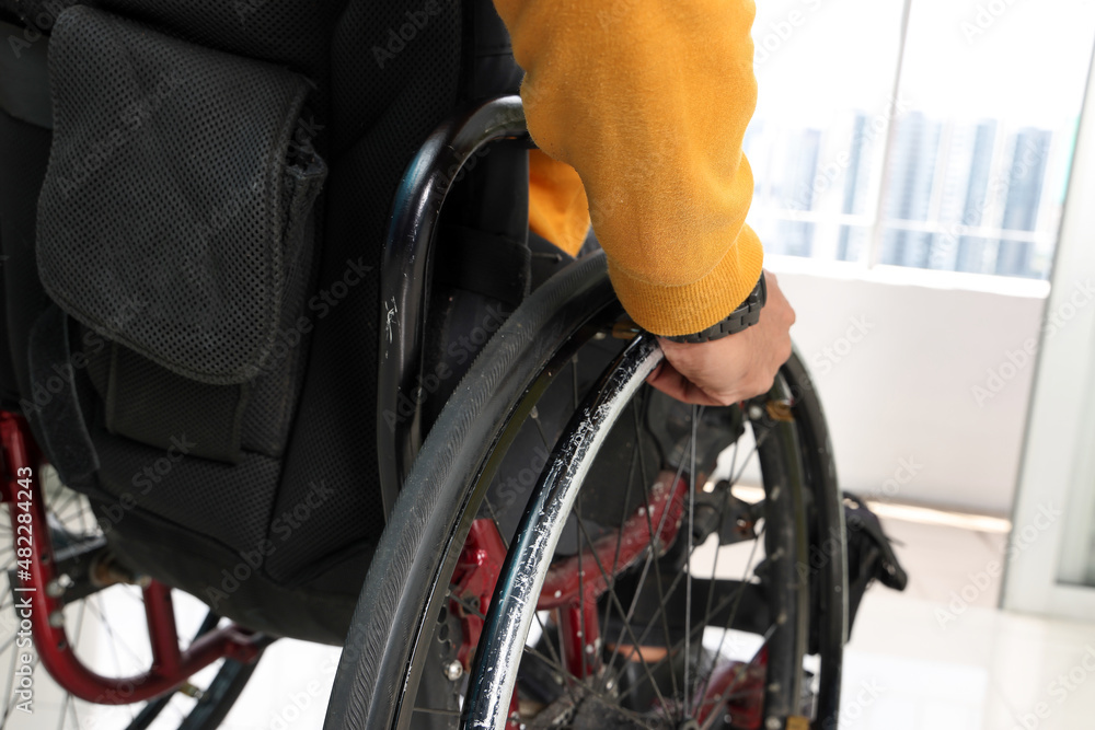 Fototapeta premium South east Asian malay middle aged disabled man on wheelchair looking sitting in front of balcony window look outside closeup hand