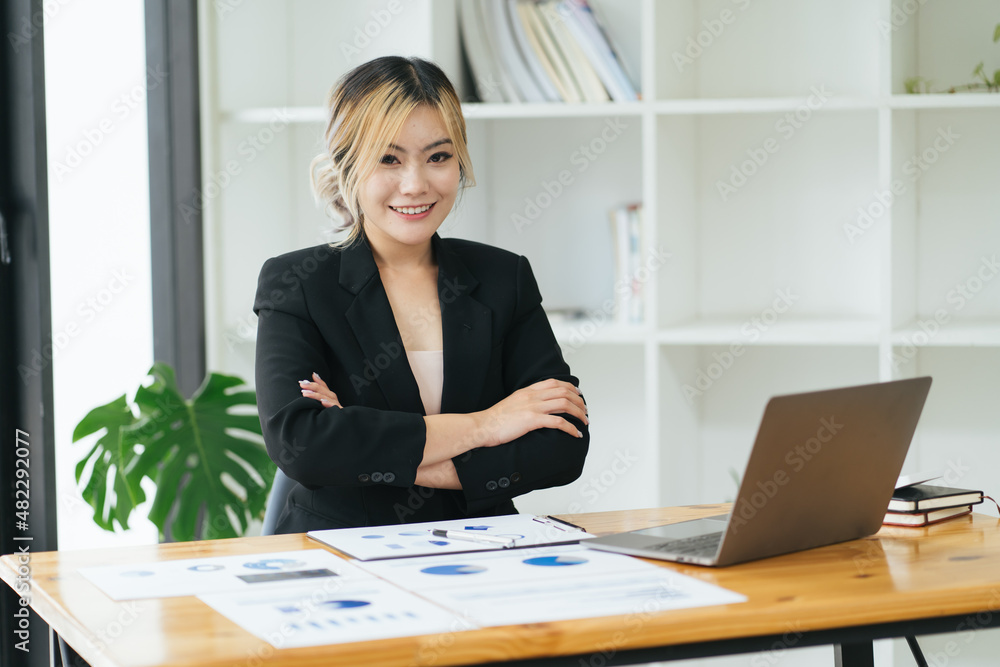 Charming Asian woman working at the office using a laptop Looking at the camera. Charming Asian woman working at the office using a laptop Looking at the camera.