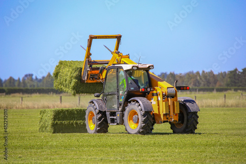A telehandler works stacking hay bales on a farm in rural Canterbury, New Zealand