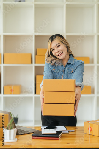 Portrait young attractive asia female owner startup business work happy with box at home prepare parcel delivery in sme supply chain, procurement, omnichannel commerce online concept.