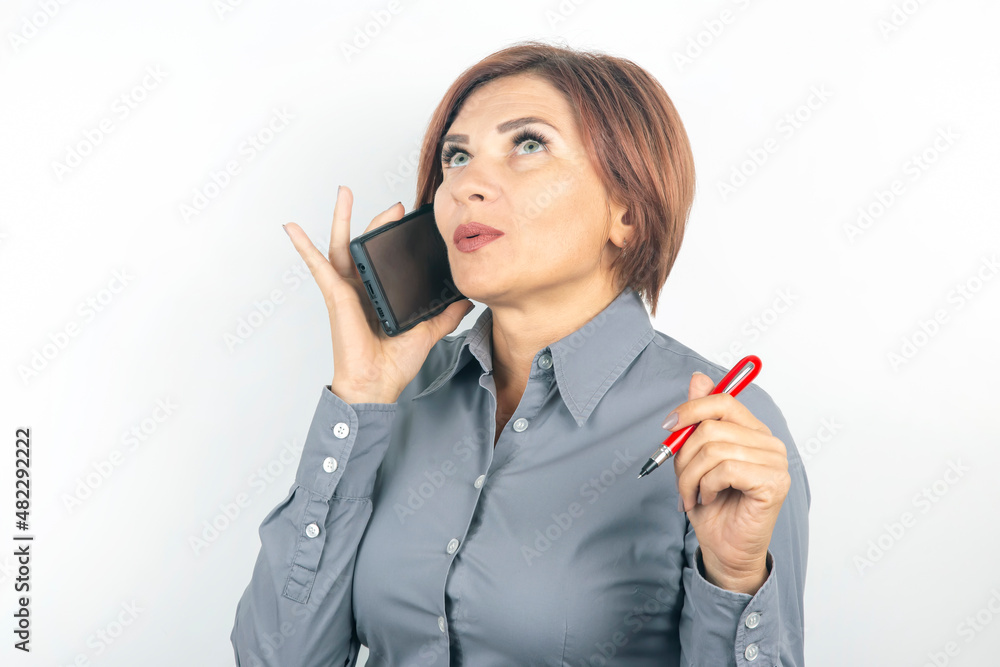 Business beautiful woman speaks on the phone with a pencil in her hand on a white background Business beautiful woman speaks on the phone with a pencil in her hand on a white background