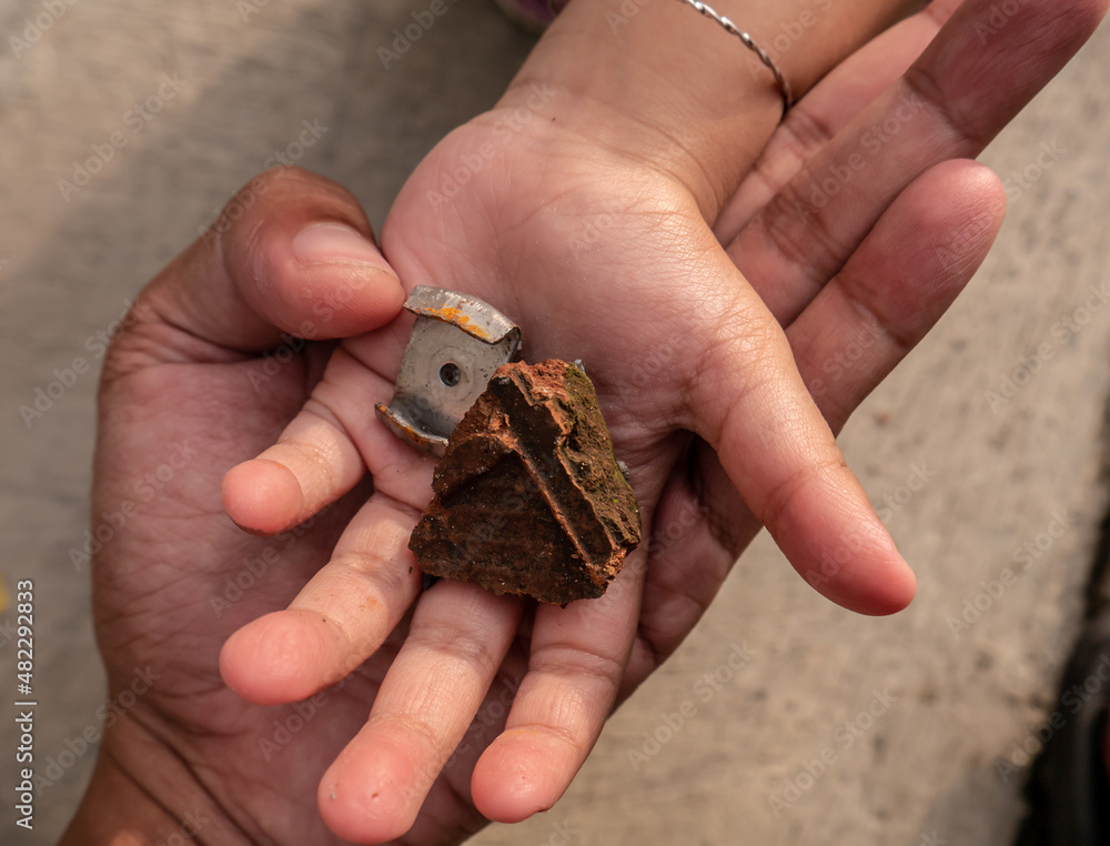 Fototapeta premium child's palm filled with shards of brick and metal on top of an adult's palm 