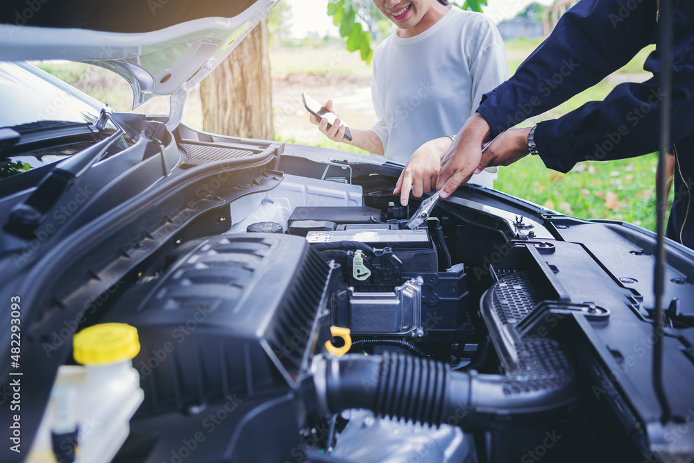 Driver woman and automobile mechanic man repairing a car engine automotive workshop checking, car service and maintenance concept Driver woman and automobile mechanic man repairing a car engine automotive workshop checking, car service and maintenance concept