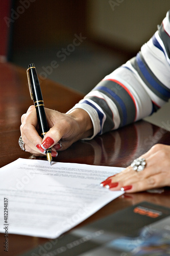 Mulher assinando um documento. (ID: 482294837)