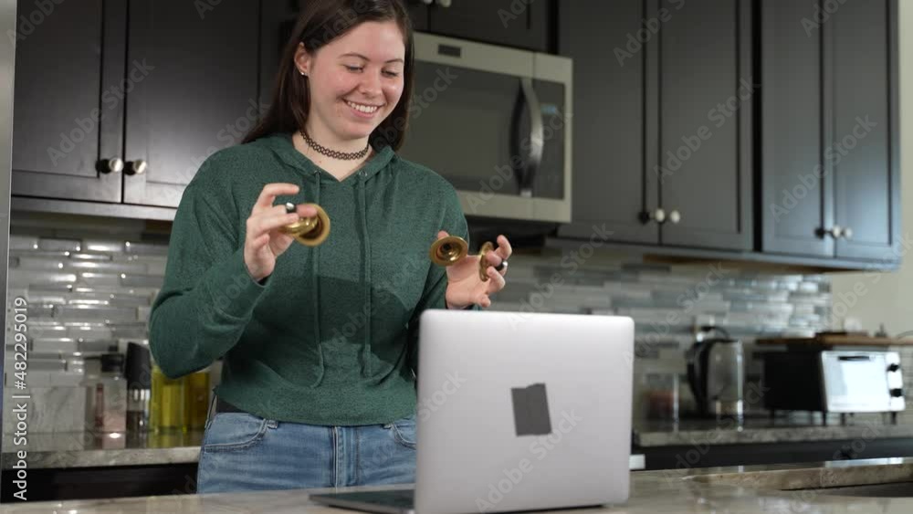 Smiling woman takes remote lesson to learn finger cymbals online on a laptop. Remote learning concept. Smiling woman takes remote lesson to learn finger cymbals online on a laptop. Remote learning concept.
