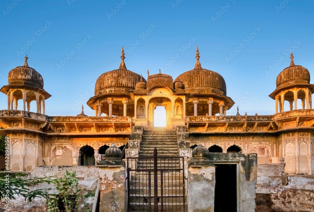 Street view of the front of an abandoned, dilapidated Indian haveli at sunrise in Mandawa, Rajasthan, with its ornate architecture and Shekhawati style painting still visible on the exterior walls.