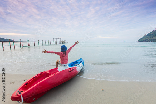 Young woman sitting on the colourful of kayak on the beach.