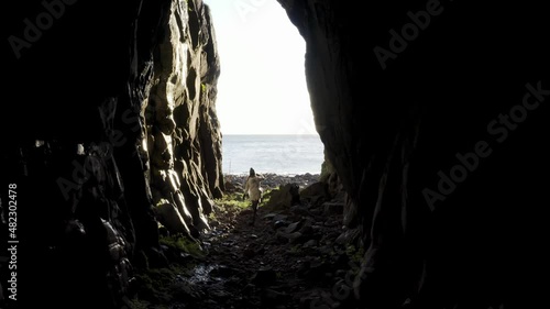 AERIAL - Person walking out of Archibald MacKinnon cave, Island Davaar, Scotland photo