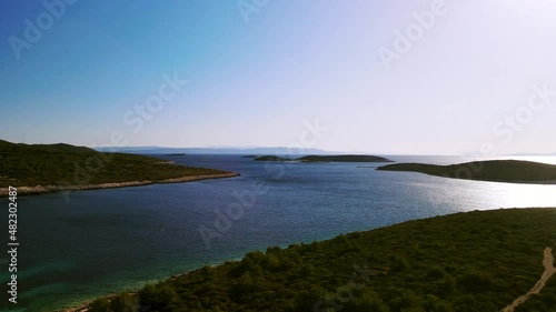 Drone shot of a beach on a tropical island with sea and small islands on the horizon with clear sky. Beautiful Mediterranean environment a famous tourist destination. Rukavac, Island Vis, Croatia 4K photo