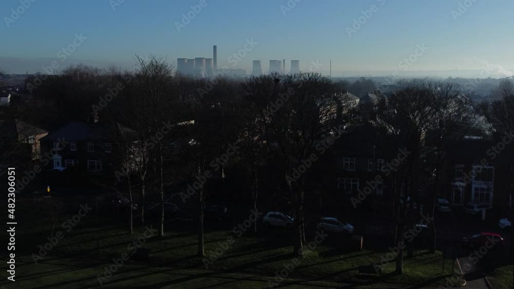 Misty English town houses under power station smokestack skyline aerial rising reveal view above trees Misty English town houses under power station smokestack skyline aerial rising reveal view above trees