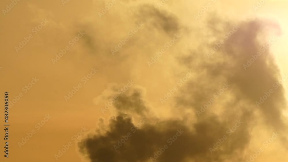 Swirling burning inferno cloud fumes whirl against sunrise orange sky Swirling burning inferno cloud fumes whirl against sunrise orange sky