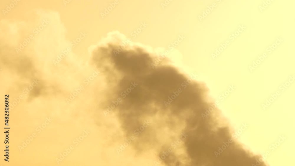 Swirling cloud fumes morphing shape shifting against sunrise orange sky Swirling cloud fumes morphing shape shifting against sunrise orange sky