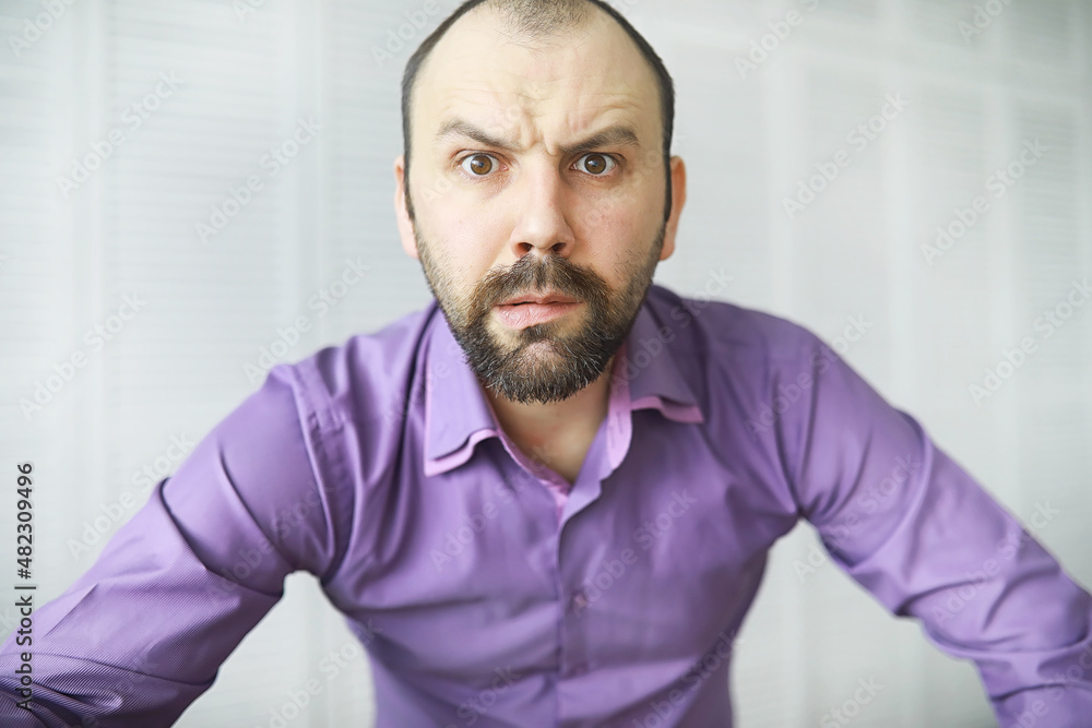 A cross-eyed bearded man is looking into the frame. Eye disease. The concept of an inexperienced specialist. Spy neighbor. A cross-eyed bearded man is looking into the frame. Eye disease. The concept of an inexperienced specialist. Spy neighbor.