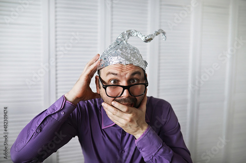 Bearded funny man in a cap of aluminum foil. Concept art phobias.Conspiracy theory. Conspiracy. Insanity.